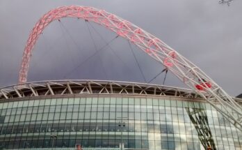 Wembley stadium under a grey sky with red lit arches