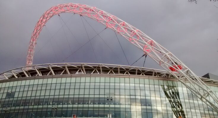 Wembley stadium under a grey sky with red lit arches