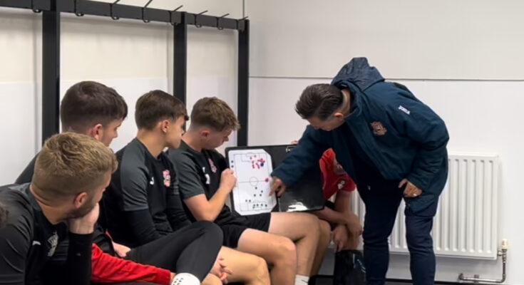 Football manager discussing tactics with a few players in a changing room