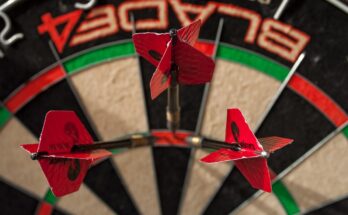 Three red flighted darts in the Treble 20 segment of a dart board.