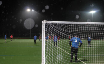 A behind the goal picture of players playing walking football on a small sided pitch.