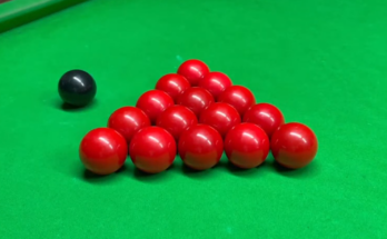 15 red snooker balls and one black ball on a snooker table