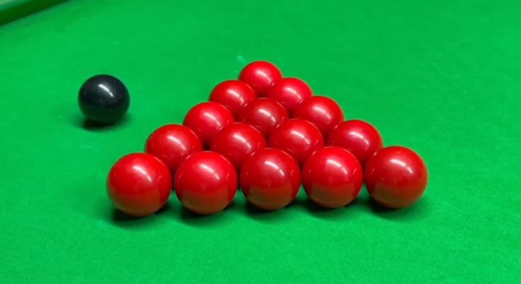 15 red snooker balls and one black ball on a snooker table