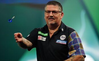 Gary Anderson throws his trademark blue flighted darts across to the right hand side of the image.