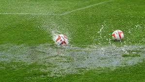 A football rolling in puddles on a watelogged pitch