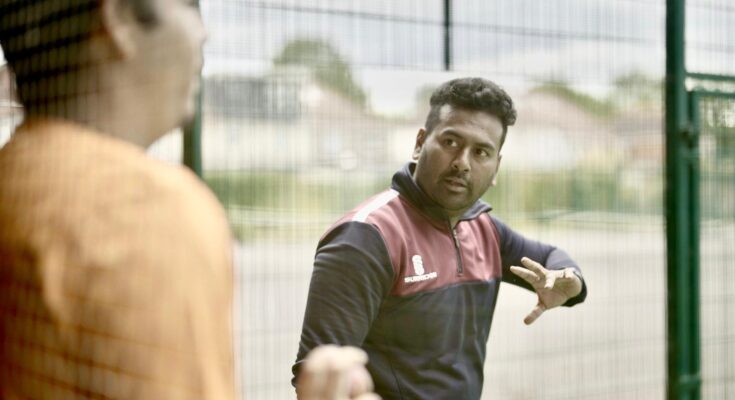 Cricket coach Tanvir Ahmed using his hands to explain a skill to a young player.