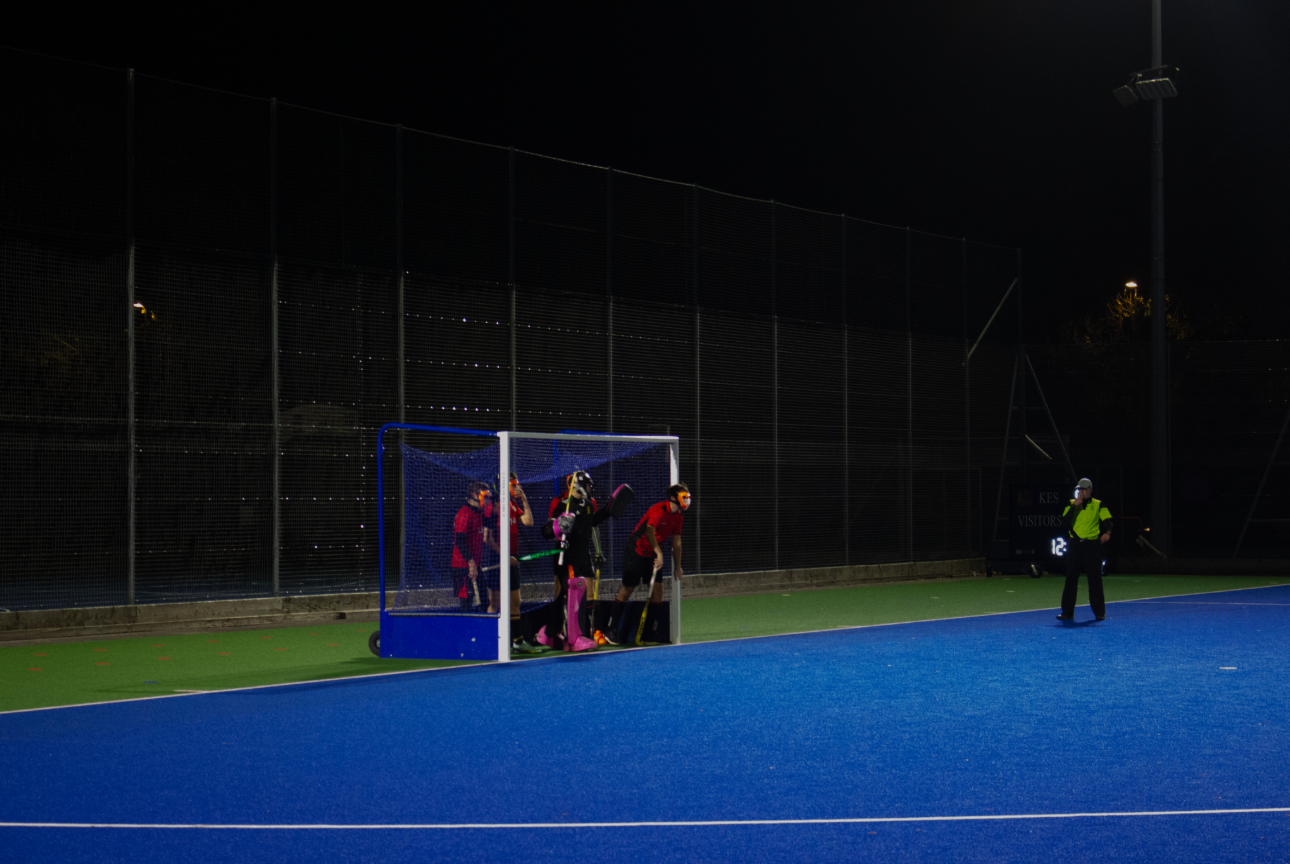 Five Solent University hockey players stand on the hockey goal line as the referee blows his whistle.