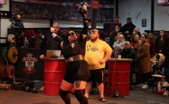 Women's Strongman Competitor lifts dumbbell over head