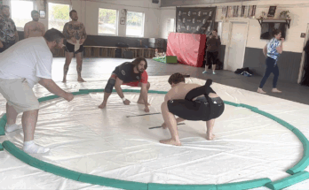 Sumo wrestler Sonny Bell is holding a pose in a Sumo ring.