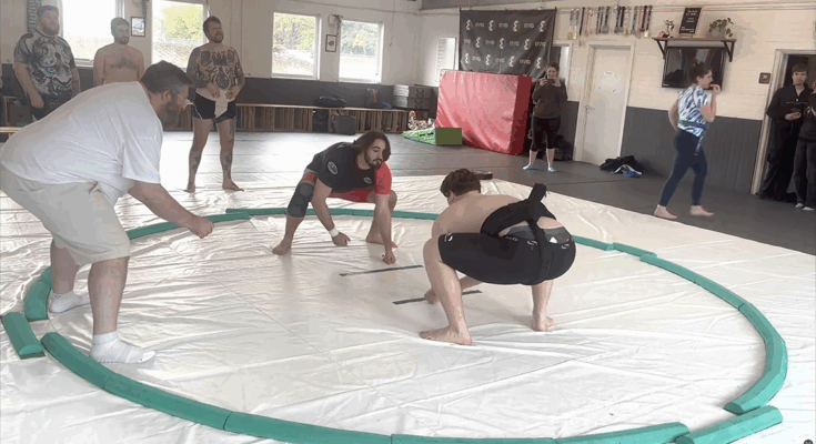 Sumo wrestler Sonny Bell is holding a pose in a Sumo ring.