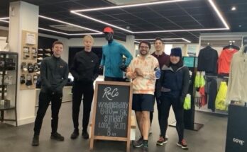 Five people stood in a run shop around a sign