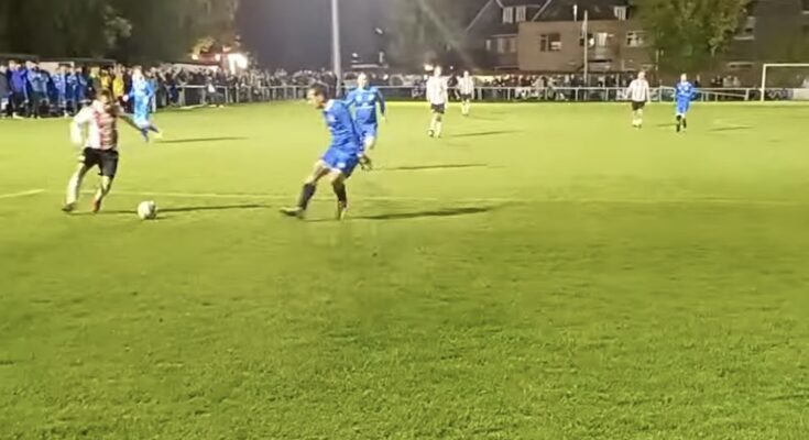 Member of Southampton legends team runs with the ball, under pressure from Brockenhurst defender.