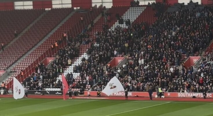 Flags of football club being waved with fans in background