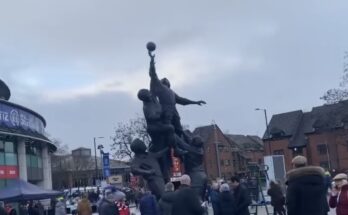 A statue of three rugby players trying to catch a ball