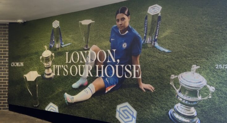 Sam Kerr surrounded by Chelsea Women's trophies.