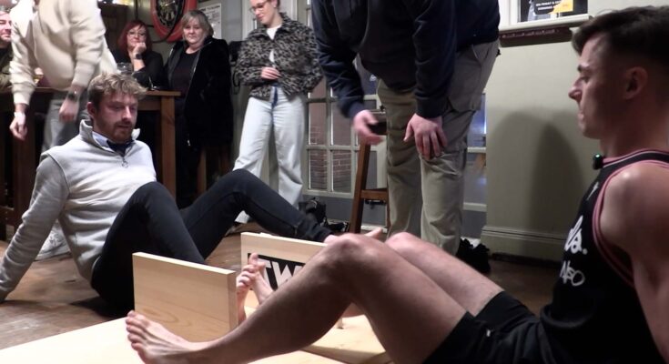 Two people toe wrestling in a pub