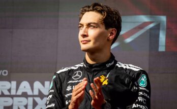 George Russell clapping with Union Jack behind him