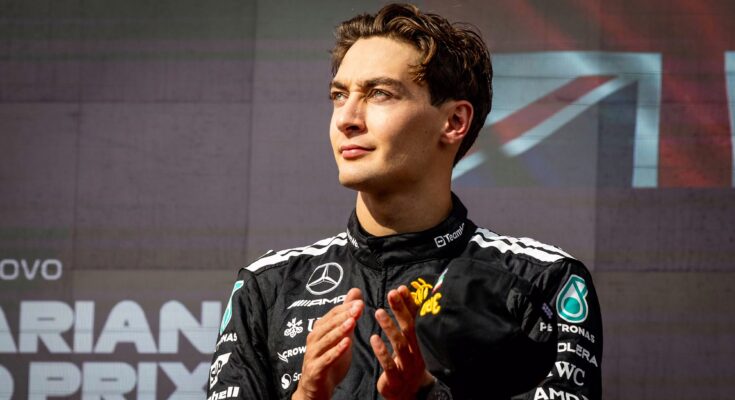 George Russell clapping with Union Jack behind him