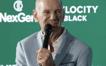 Adrian Newey holding a microphone.