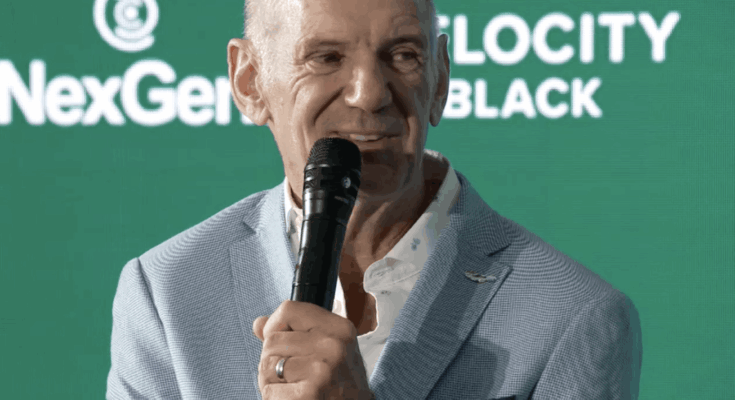 Adrian Newey holding a microphone.