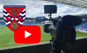 Camera pointing onto pitch with YouTube logo and Dagenham and Redbridge badge.