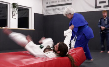 Judoka Leah Cozens throws another participant onto a red mat whilst learning.