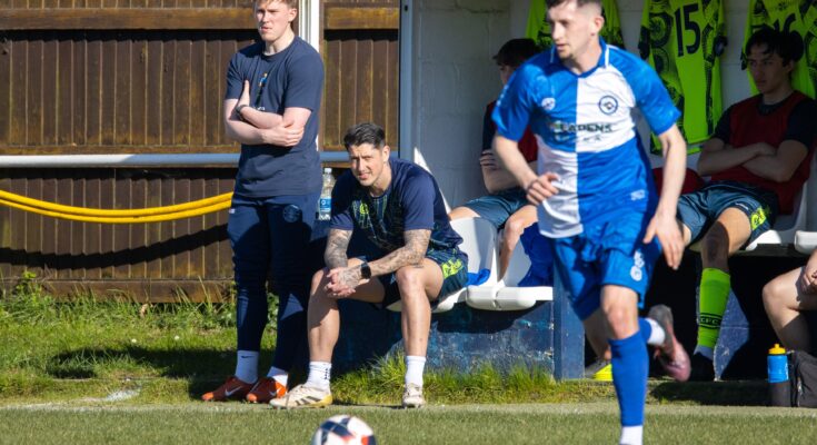 Christchurch player running to ball with Christchurch coaches stood and sat behind him.