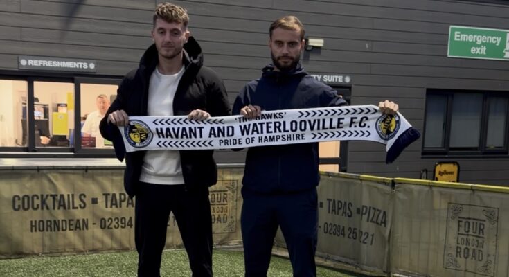 Two football managers holding a scarf on a football pitch.