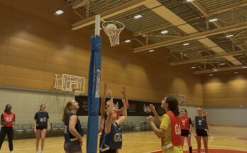 Netballers shooting a ball into a hoop.