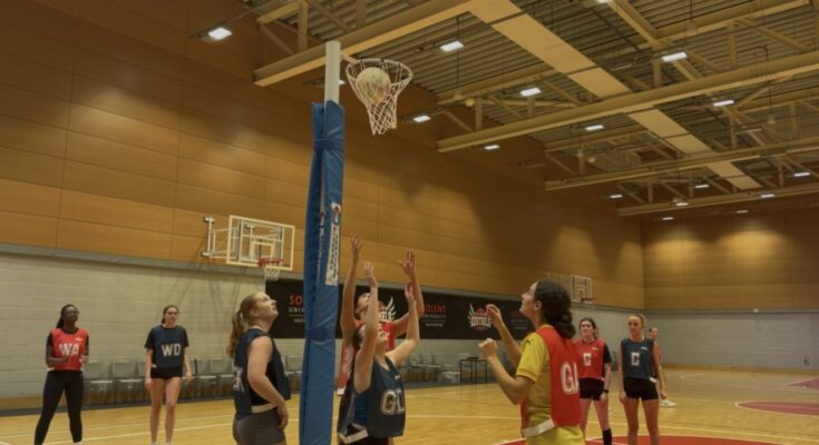 Netballers shooting a ball into a hoop.