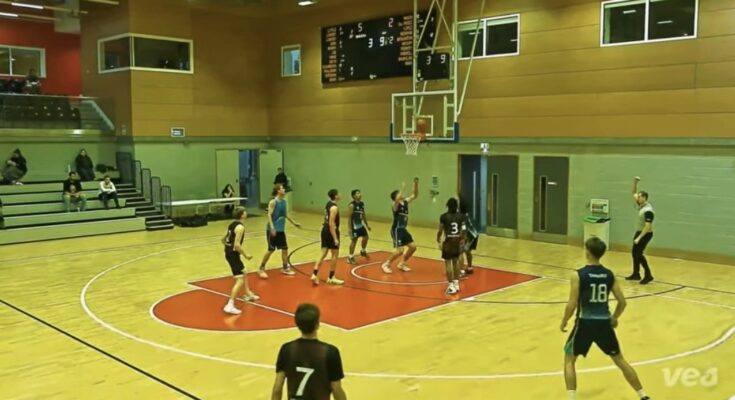 Basketball player shooting ball into hoop during match