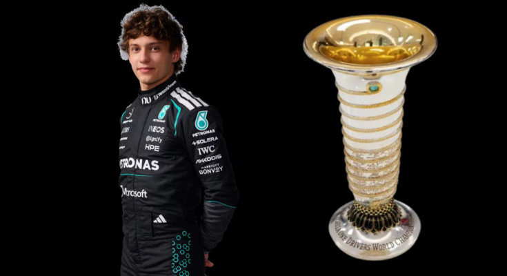 Driver in black racing suit posing with a trophy to the right of them.